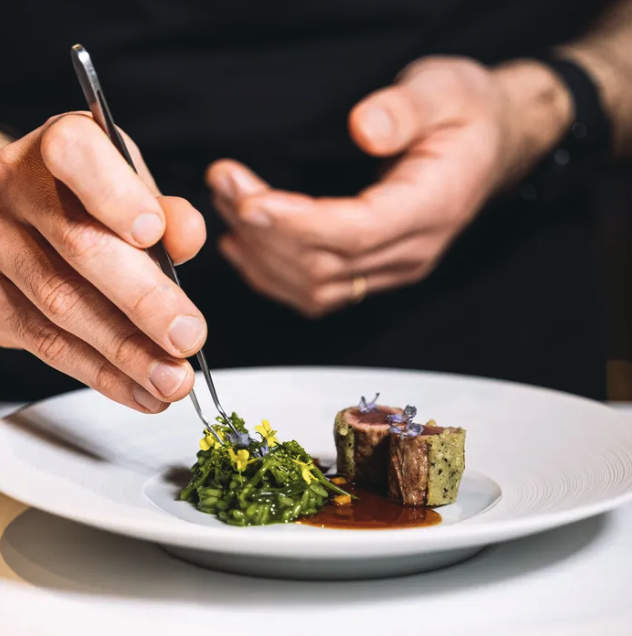 chef die een gerecht met pincet opmaakt